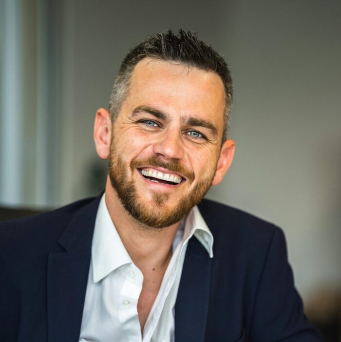 Business professional in suit smiling confidently in a modern office environment.